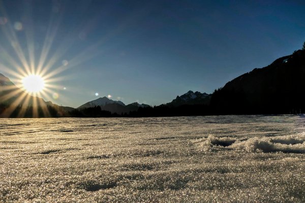 Sonnenuntergang über den Bergen. Davor frischer, unverspurter Schnee.